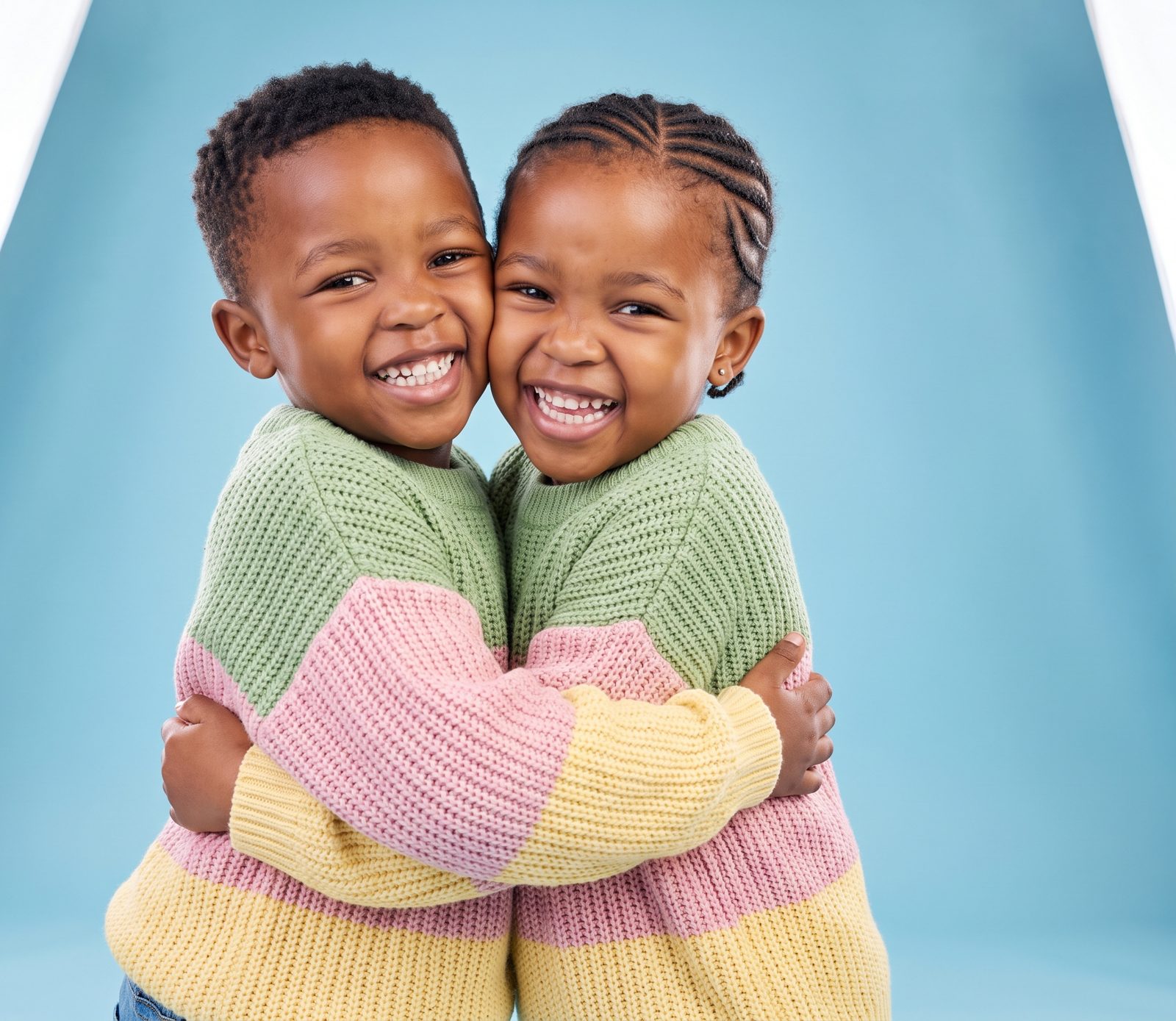 Two little ones hugging and laughing in colourful jumpers